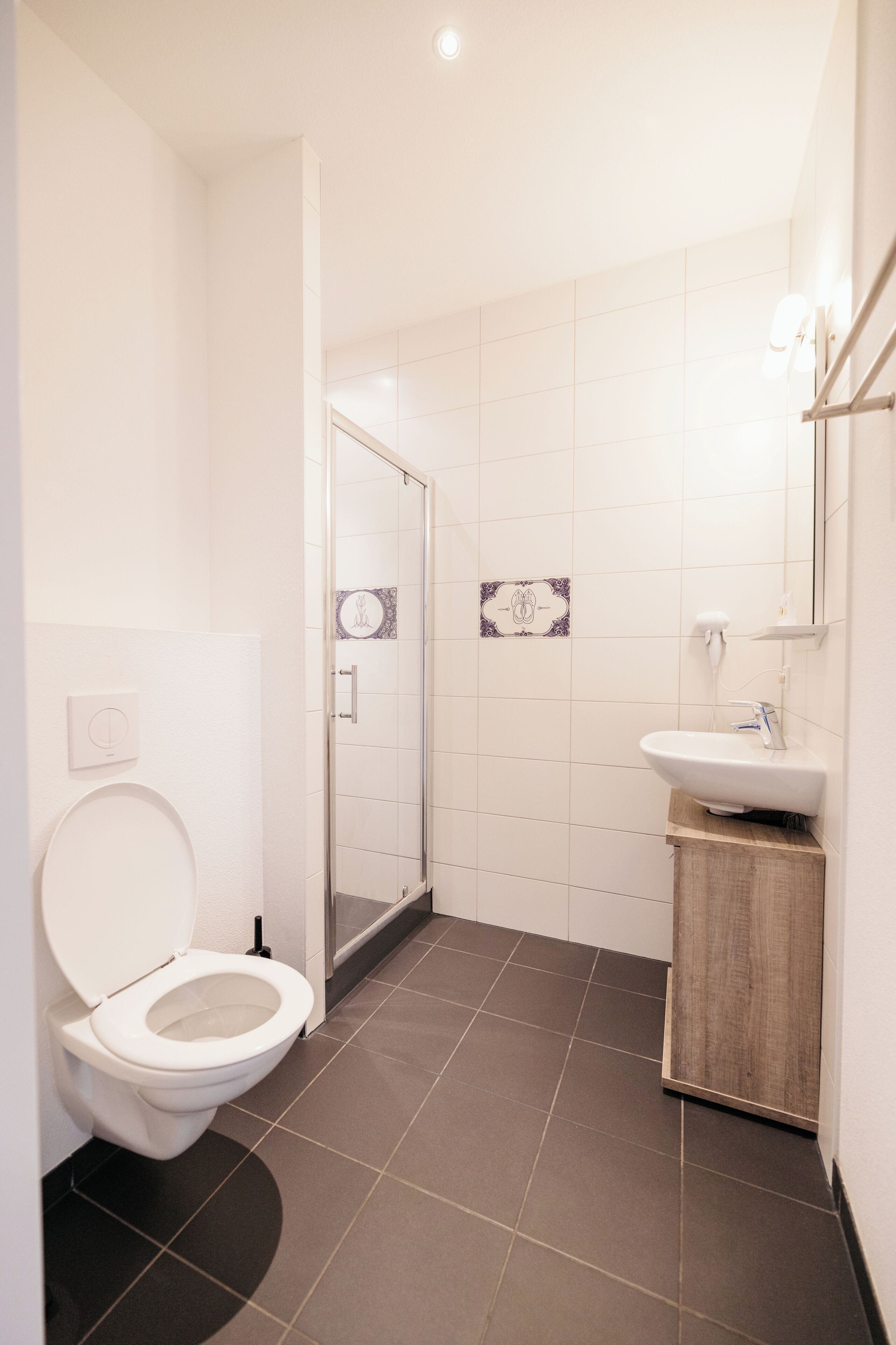 A modern bathroom with a toilet, shower, and sink.