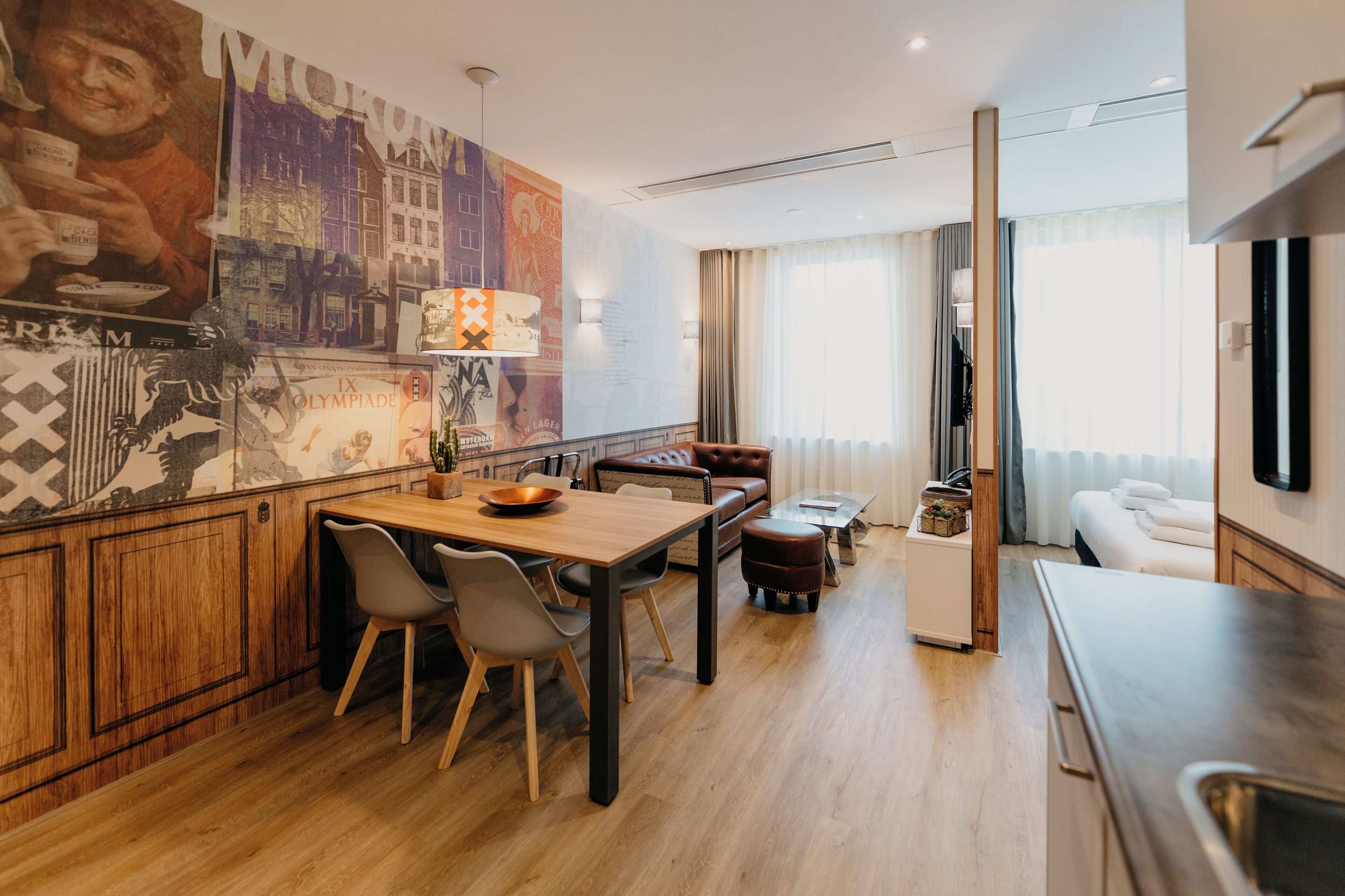 Una habitación de hotel moderna con una mesa de comedor de madera, sillas, un sofá, una mesita de centro y una cama.