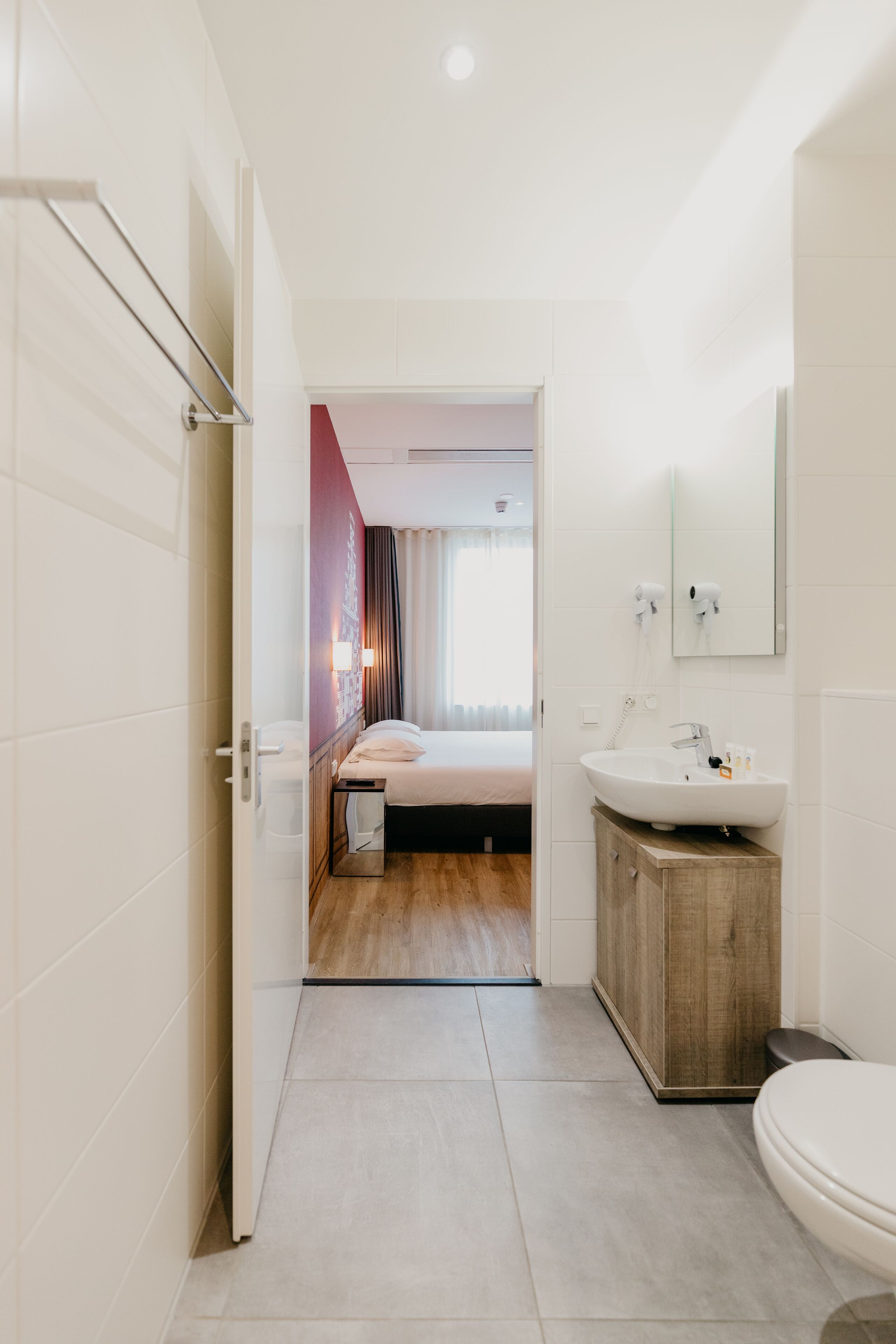 Ein modernes Badezimmer in einem Hotel, mit einem großen Waschbecken, einer Toilette und einer Duschkabine.