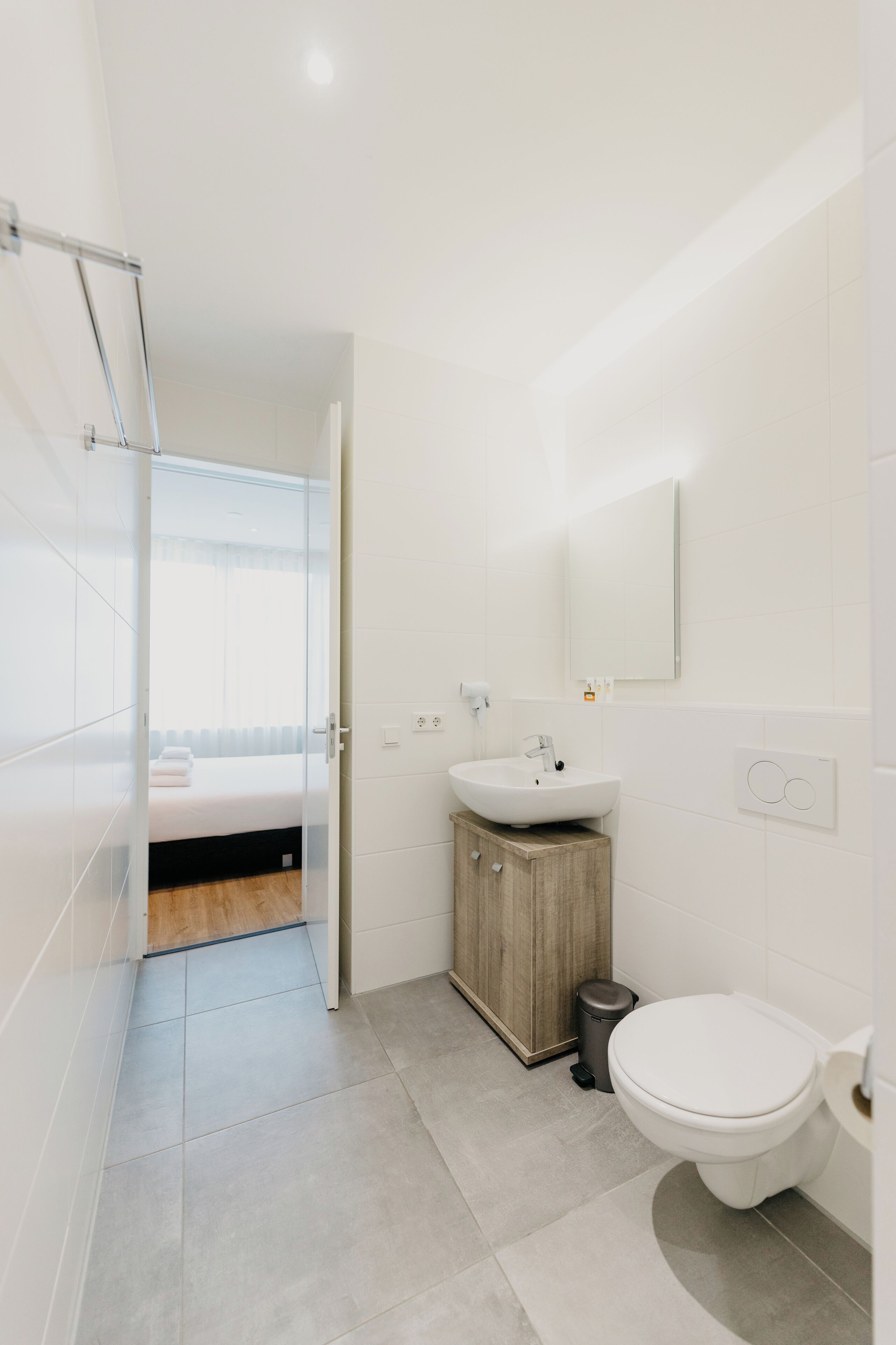 A modern bathroom with a white sink, toilet, and glass shower enclosure.