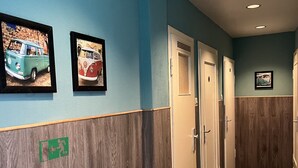 A hallway with blue walls, wooden paneling, and framed pictures of vintage cars. - Hotel Schwarzer Bär (Hannover)