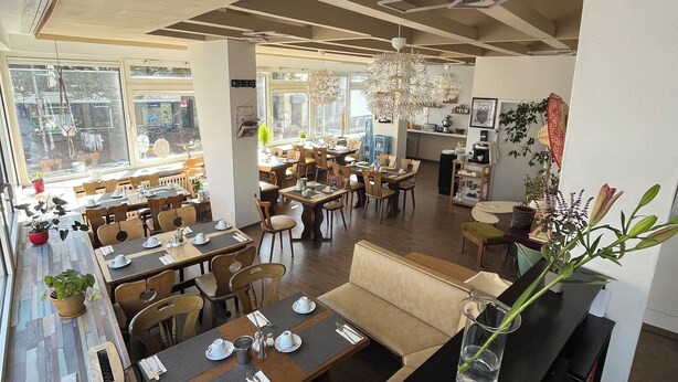 A restaurant with multiple dining areas, including a bar and seating arrangements. - Hotel Schwarzer Bär (Hannover)