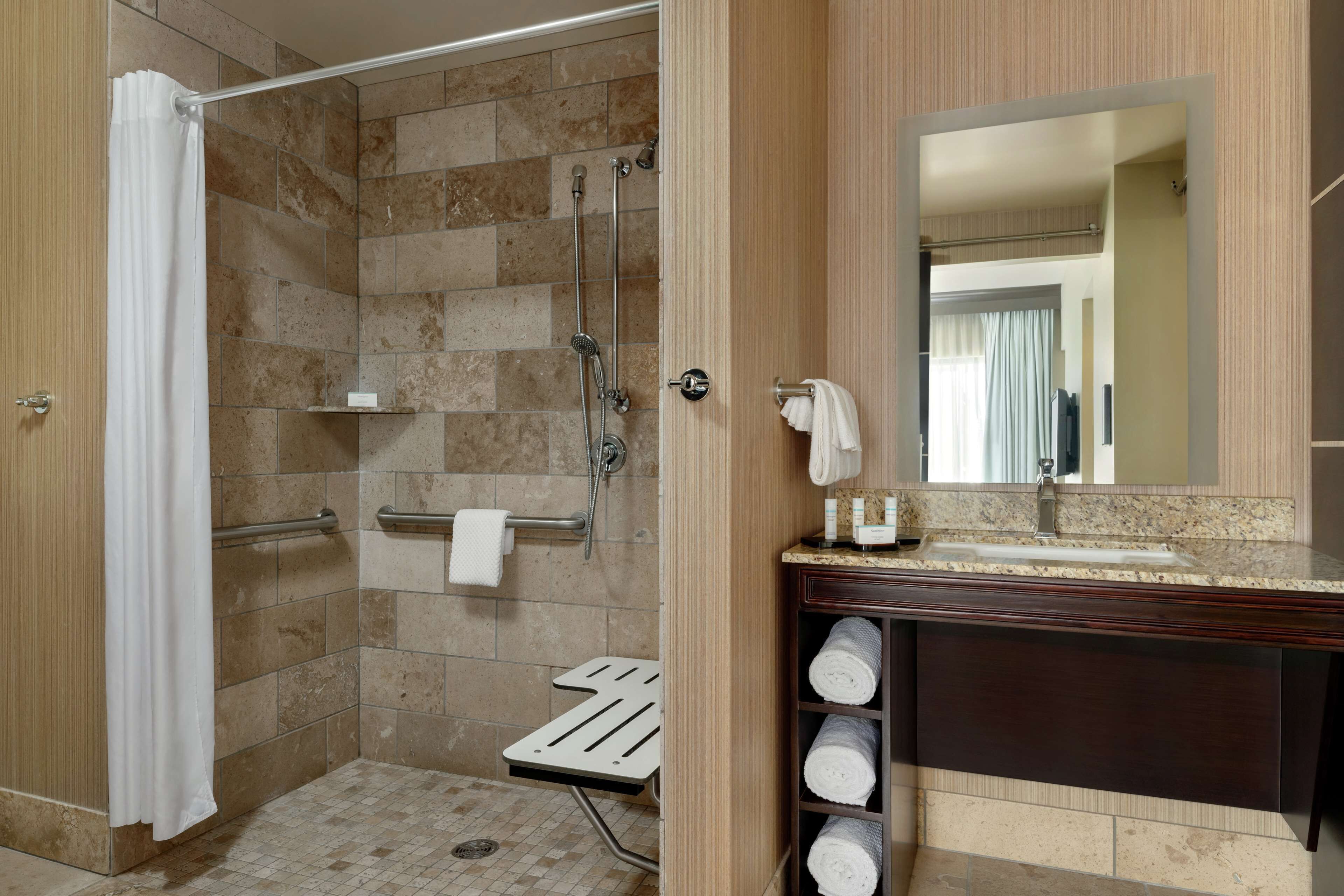A bathroom with a shower, a towel rack, a sink, and a mirror.