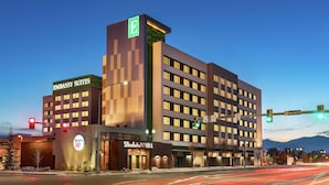 Um hotel com vários andares, com uma placa chamativa 'Embassy Suites', um restaurante 'Shades 347' e vista para montanhas ao fundo.