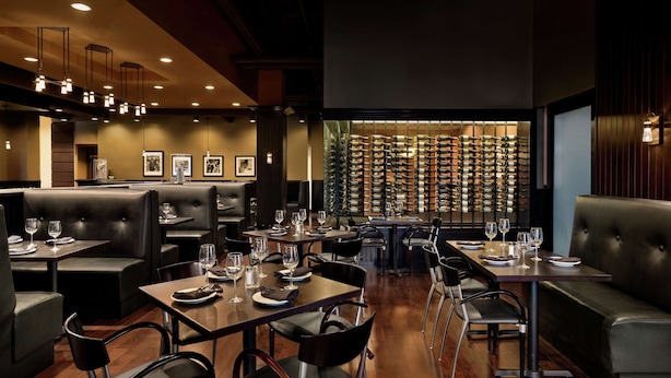 Um restaurante com cabines e mesas, cada conjunto com copos de vinho e pratos.