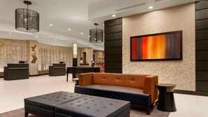 Um lobby moderno com balcão de recepção, área de estar e uma grande pintura abstrata na parede.