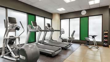 Une salle de sport équipée de tapis de course, de vélos elliptiques et d’un vélo d’appartement.