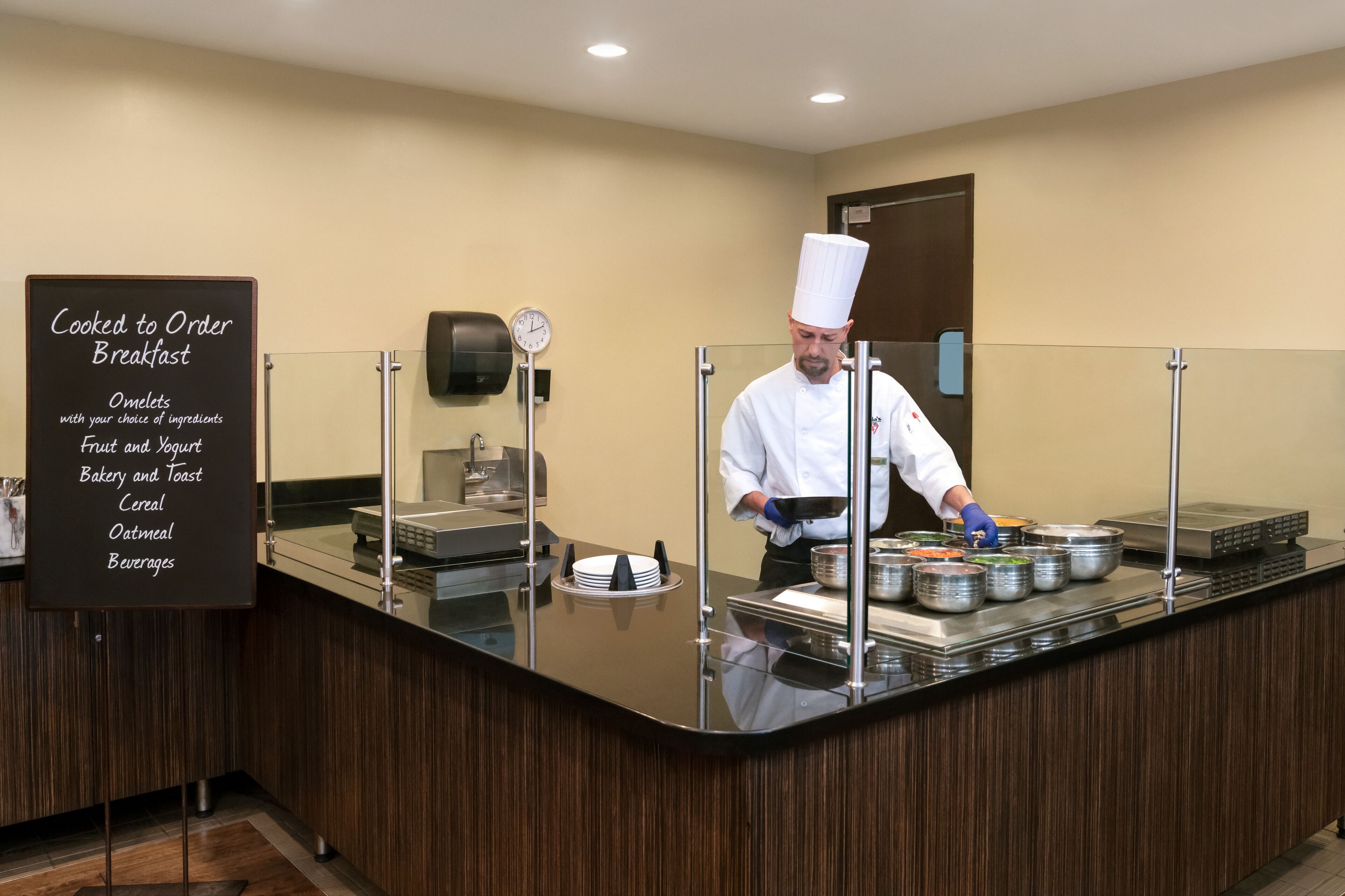 A breakfast buffet area with a chef preparing food.