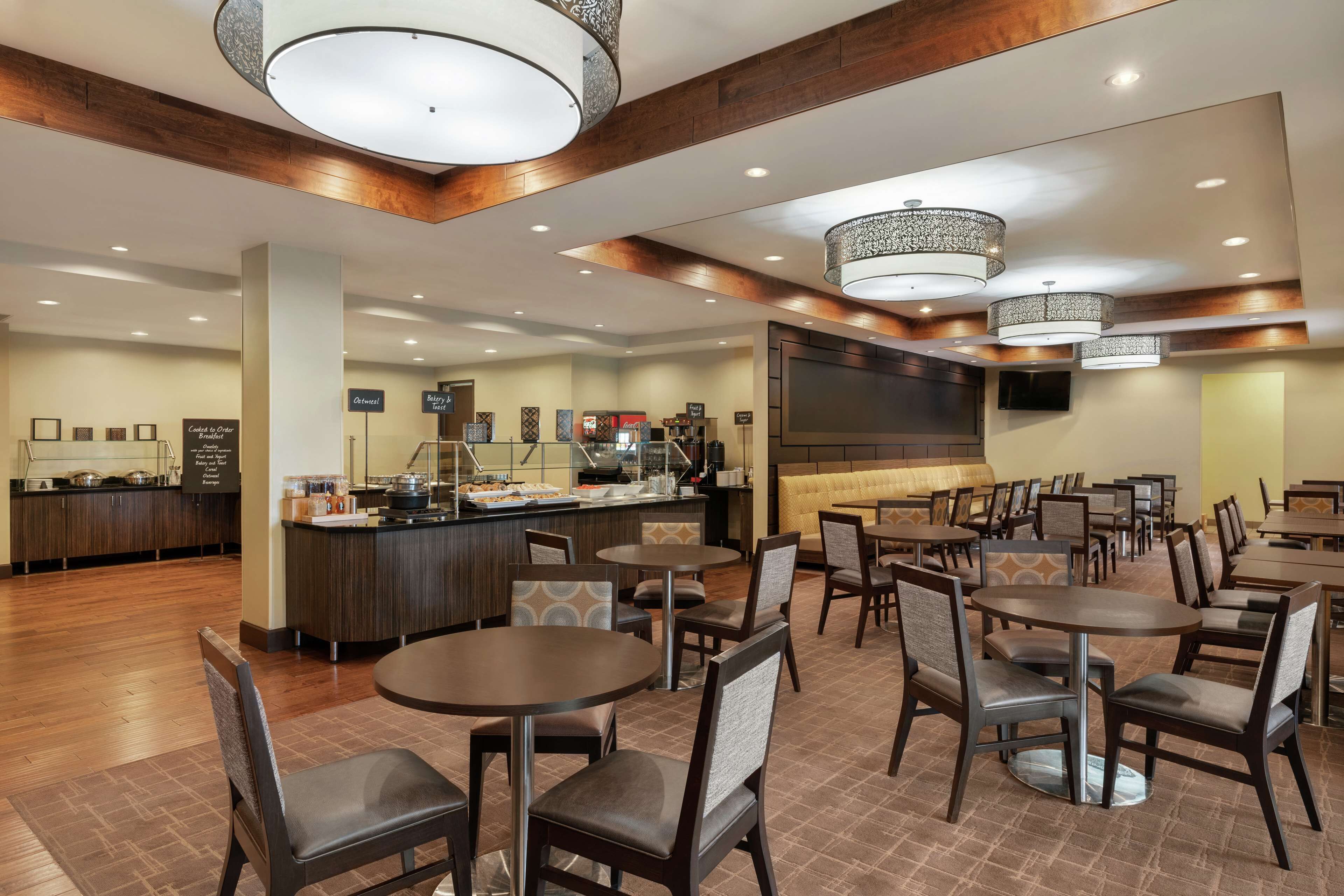 A hotel lobby with multiple seating areas, a reception desk, and a buffet.