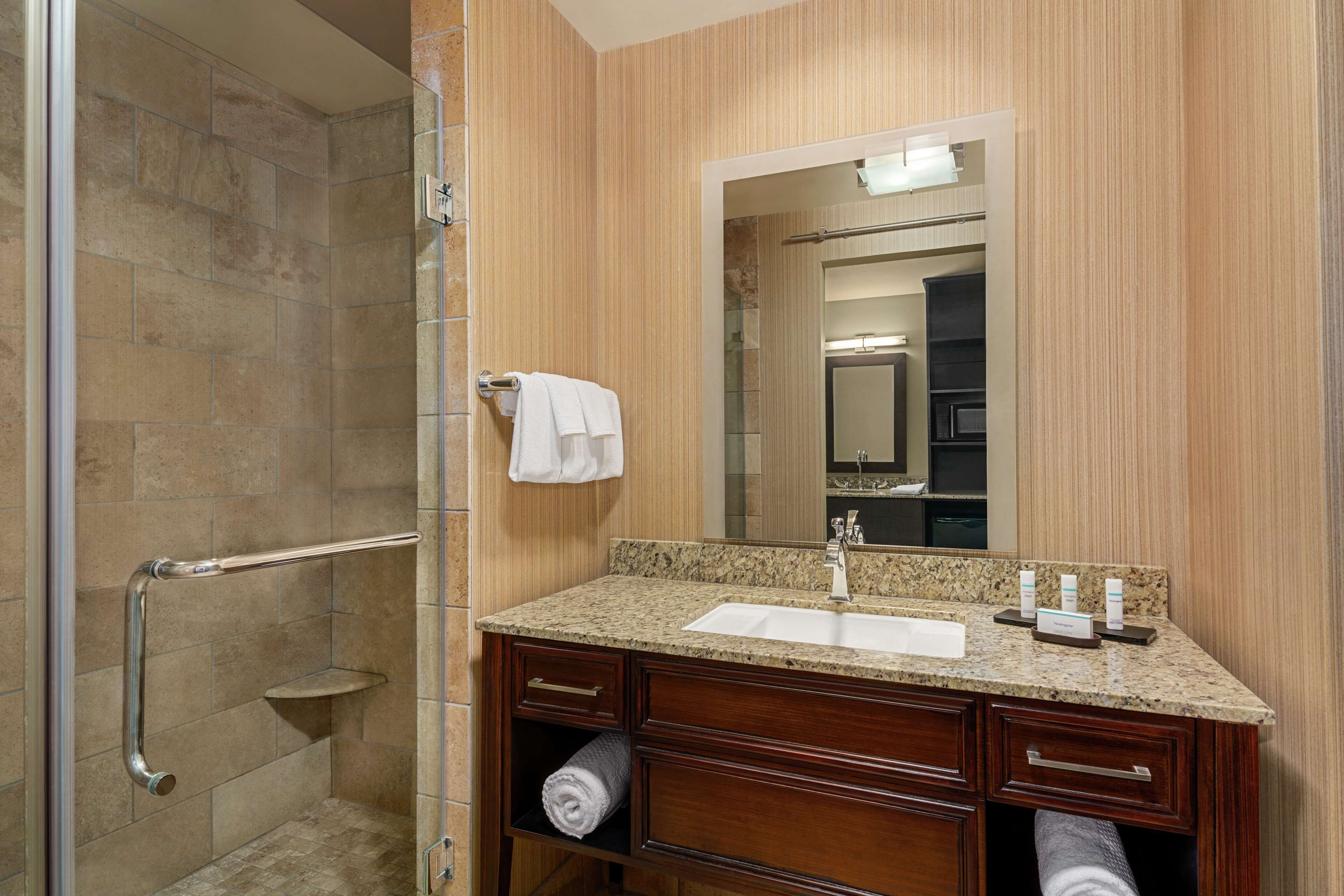 Une salle de bain équipée d’une douche, d’un lavabo, d’un miroir et de meubles en bois.