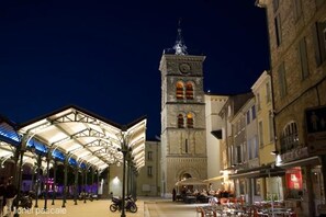 Un bâtiment historique doté d’une tour horlogée, d’un marché couvert et d’une rue bordée de boutiques.
