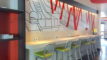 A long counter with bar stools, a large wall mural, and a digital screen.
