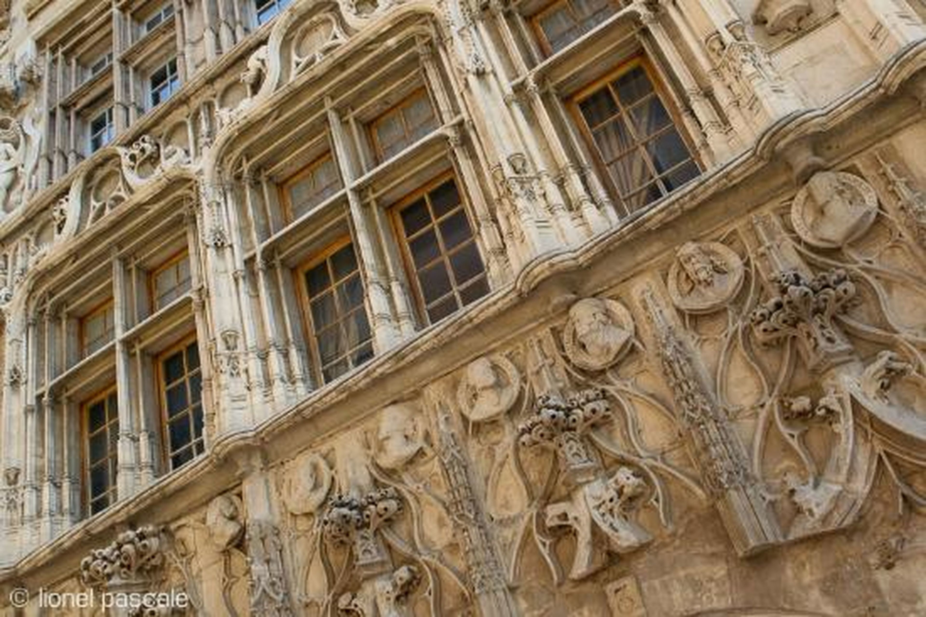 Fachada de edificio con detalles arquitectónicos ornamentales, incluyendo figuras esculpidas y molduras decorativas.