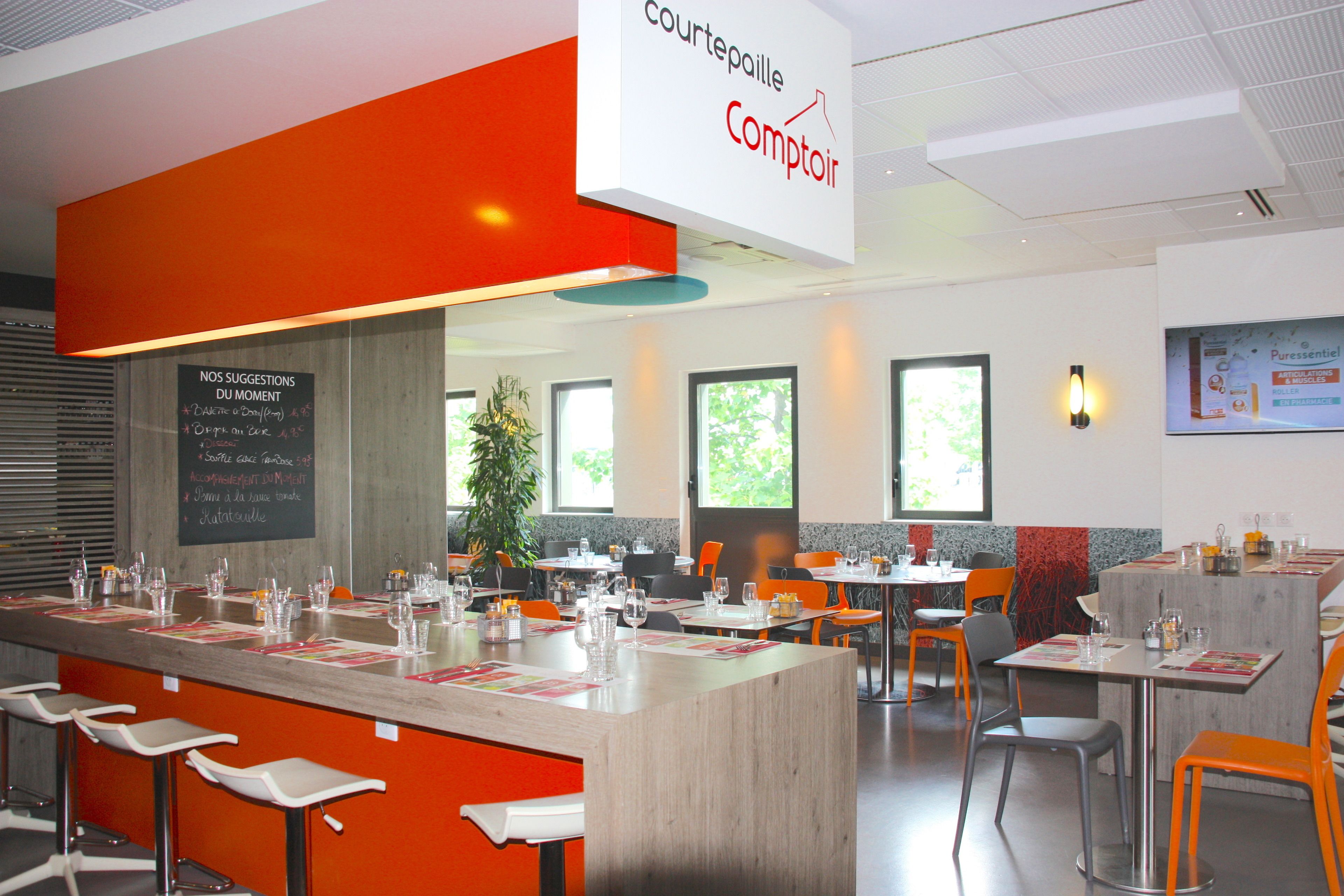 A modern restaurant with a central bar area, multiple tables, and chairs.