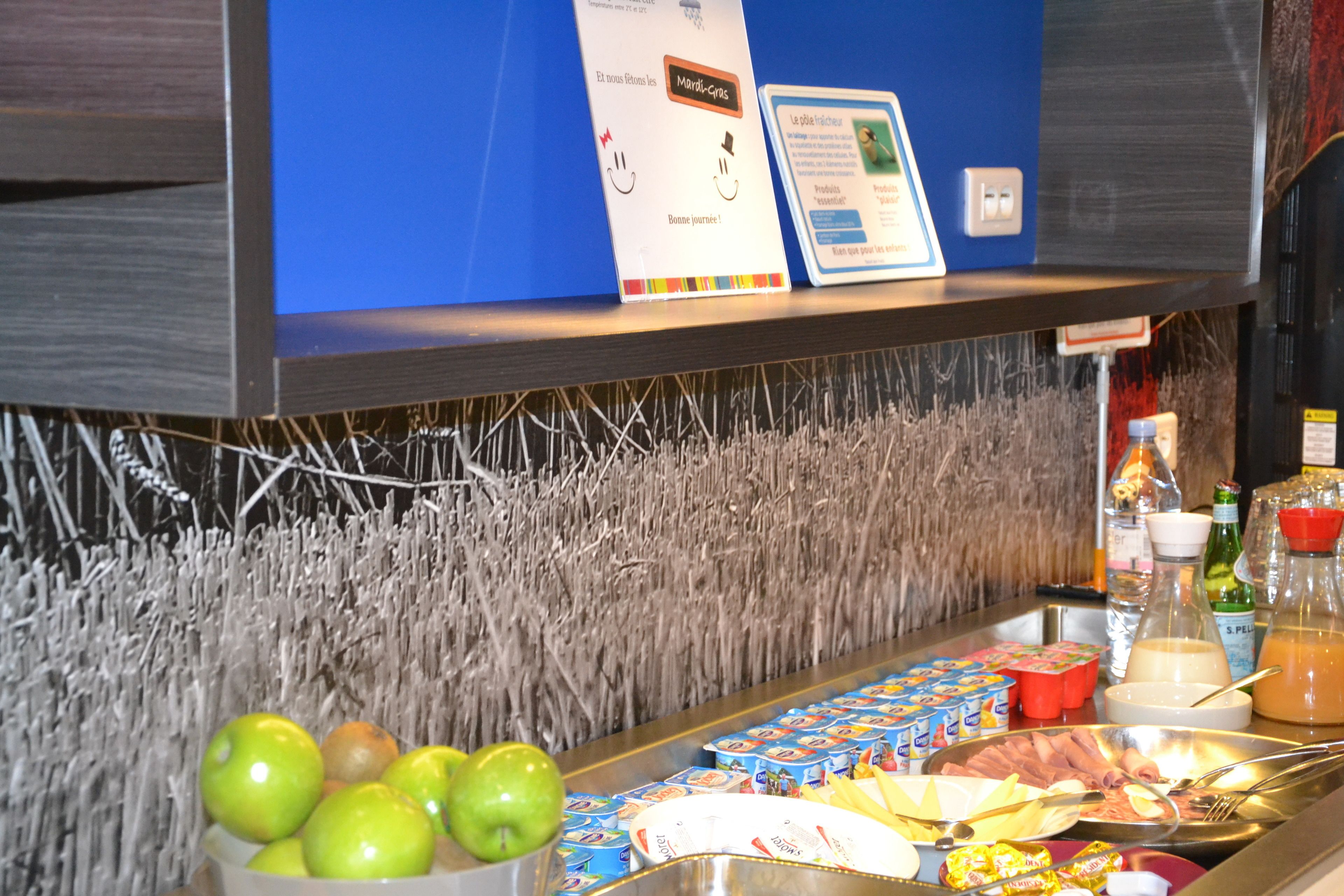 A breakfast buffet with various food items, a sign with a greeting, and a blue wall in the background.