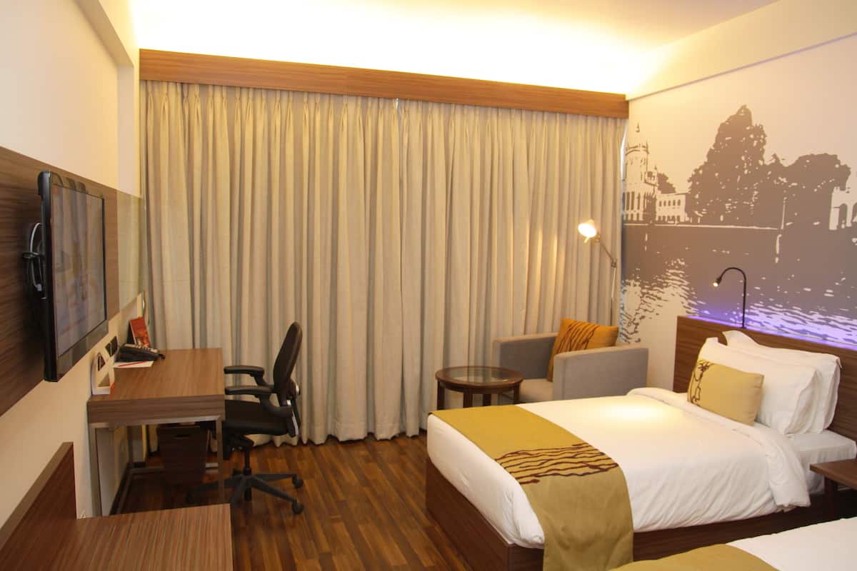 Une chambre d’hôtel avec un lit, un bureau, une chaise et une grande fenêtre avec des rideaux.
