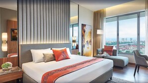 A modern hotel room with a large bed, a desk, and a view of a cityscape.