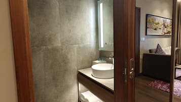 A modern bathroom with a large mirror, a round sink, and a glass-enclosed shower.