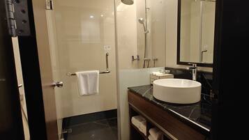 A modern bathroom with a glass-enclosed shower, a white sink, and a large mirror.