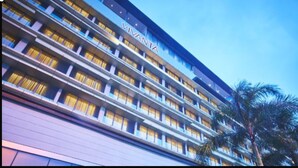 A multi-story hotel with a modern design, featuring balconies with curtains and a prominent brand name on the facade.