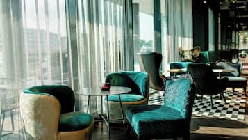 A modern lounge area with a checkered floor, a round table, and several upholstered chairs.