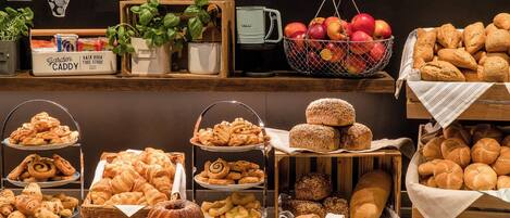 A bakery display with various breads, pastries, and a coffee machine.