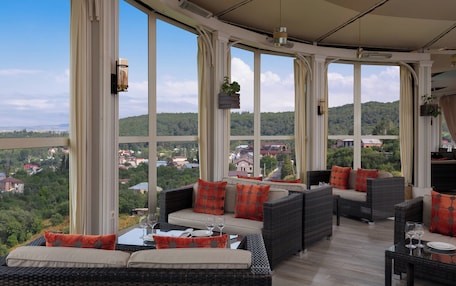 A sunroom with large windows, wicker furniture, and a view of a green landscape.