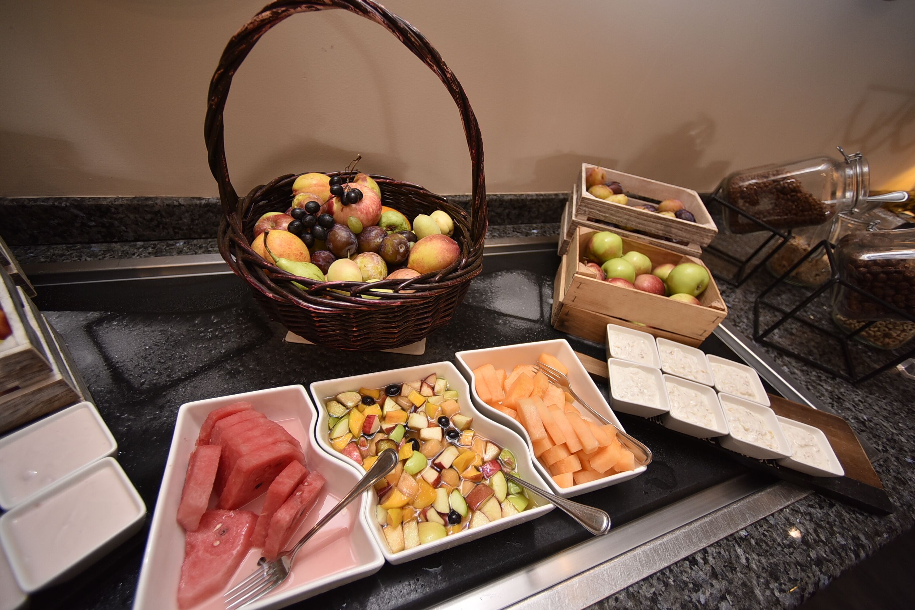 A buffet table with various fruits and vegetables, including watermelon, apples, and carrots.