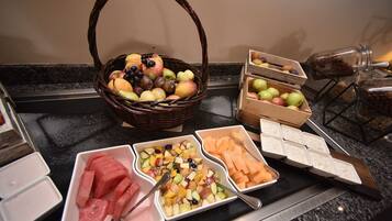 A buffet table with various fruits and vegetables, including watermelon, apples, and carrots.