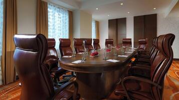 Un salón de conferencias con una mesa redonda, ocho sillas de cuero y piso alfombrado.