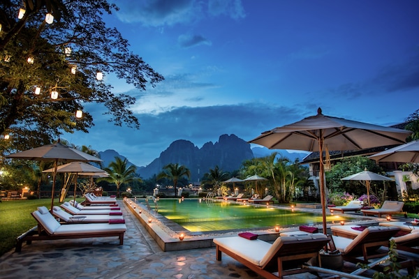 Una piscina al aire libre, sombrillas, sillones reclinables de piscina