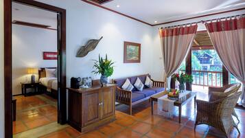 A spacious living area with a sofa, a wooden cabinet, a dining table, and a view of the outdoors.