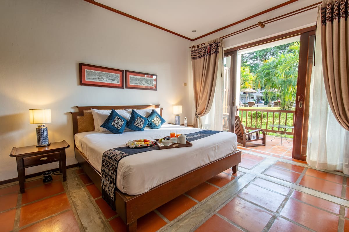 Une chambre à coucher avec un grand lit, deux tables de chevet, une commode et une vue sur l’extérieur.