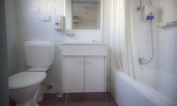 A bathroom with a toilet, sink, mirror, and shower. - Herston Place Motel (Herston)