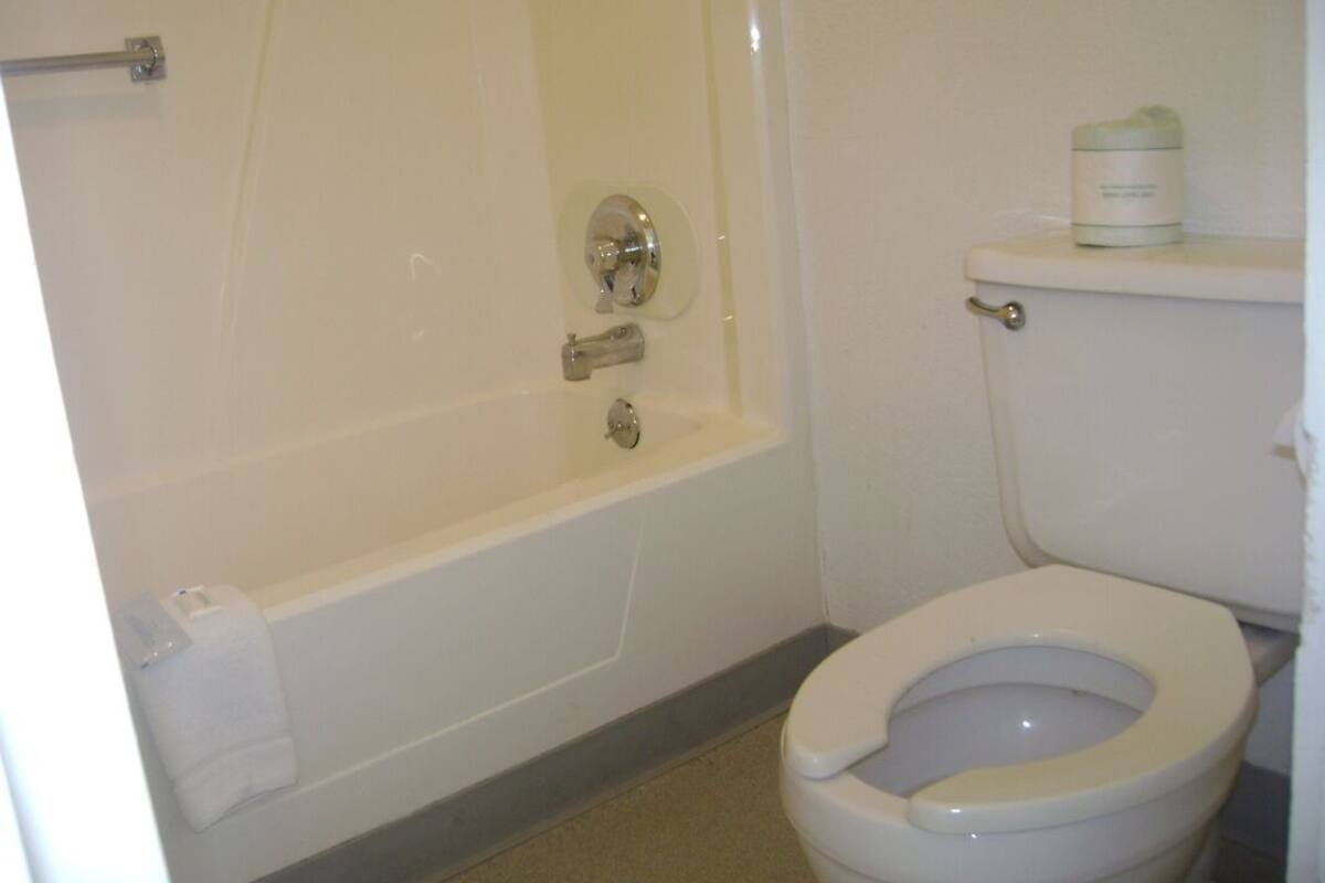 A bathroom with a bathtub, toilet, and a towel rack.
