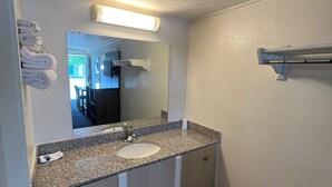 A bathroom with a granite countertop, two sinks, a mirror, and a towel rack. - Motel Beechmont (Cincinnati)