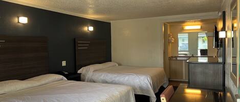 A hotel room with two beds, a desk, and a mirror.