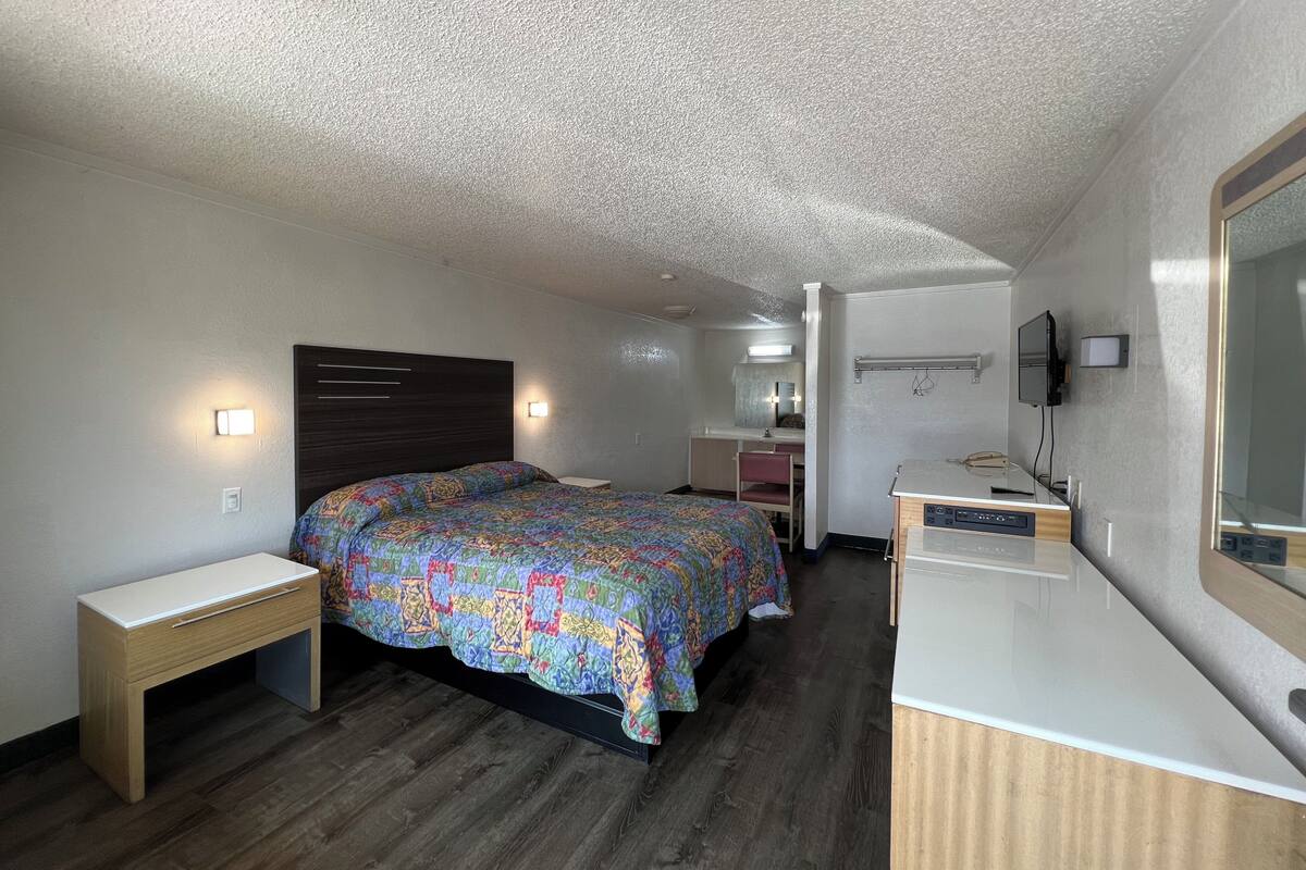 A bedroom with a bed, bedside tables, a desk, and a mirror.