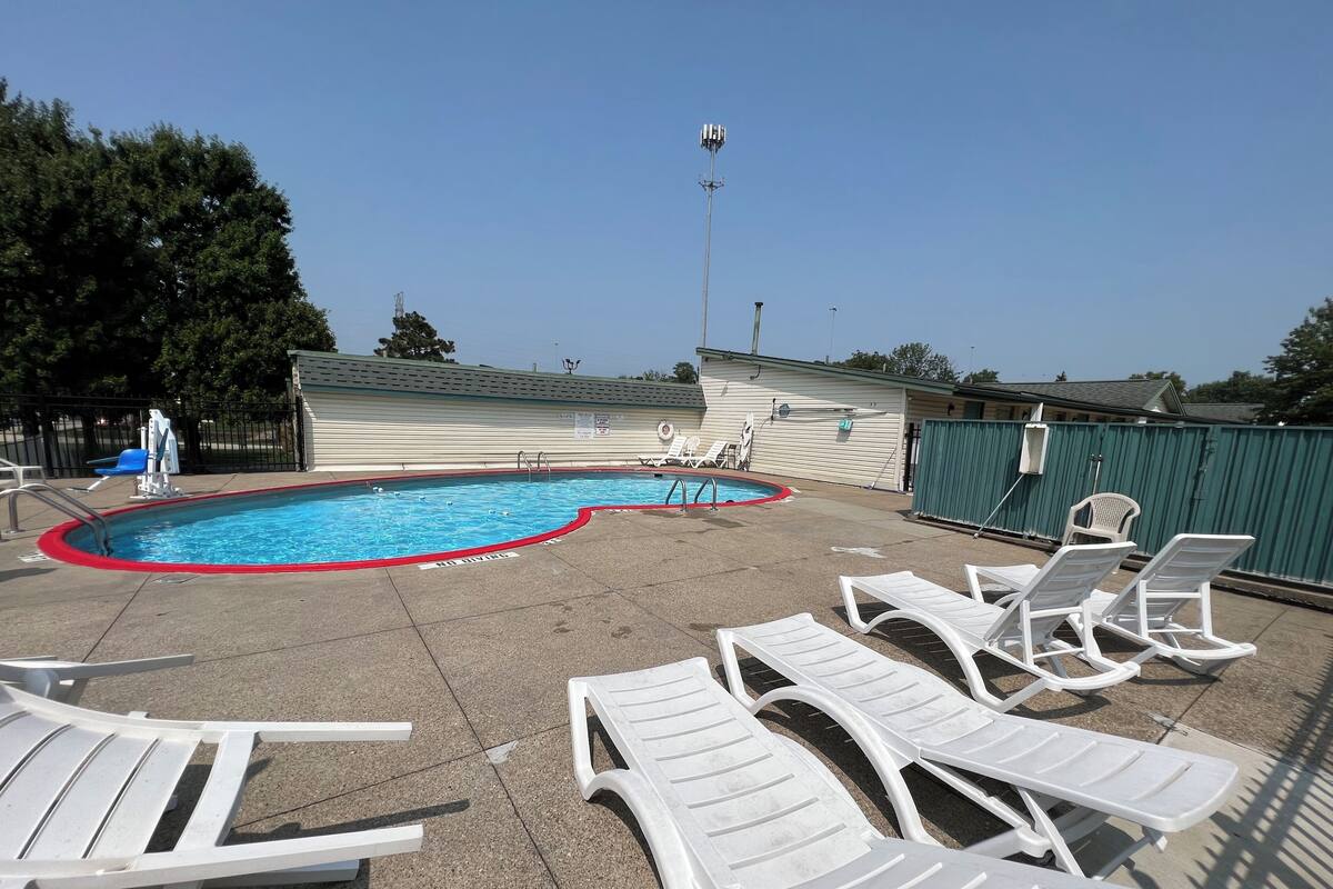 A swimming pool with lounge chairs and a covered area.
