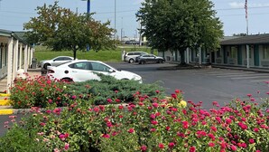 A motel with a large sign, parked cars, and a flower garden. - Motel Beechmont (Cincinnati)