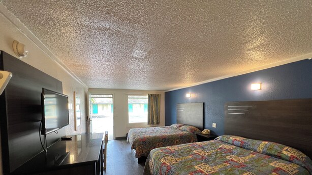 A hotel room with two beds, a desk, a TV, and a door leading to a balcony. - Motel Beechmont (Cincinnati)