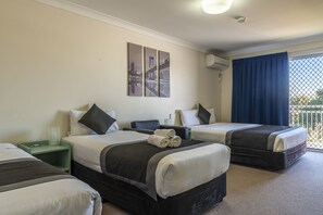 A hotel room with two beds, a nightstand, a wall-mounted air conditioner, and a window with a view. - Chermside Court Motel (Chermside)