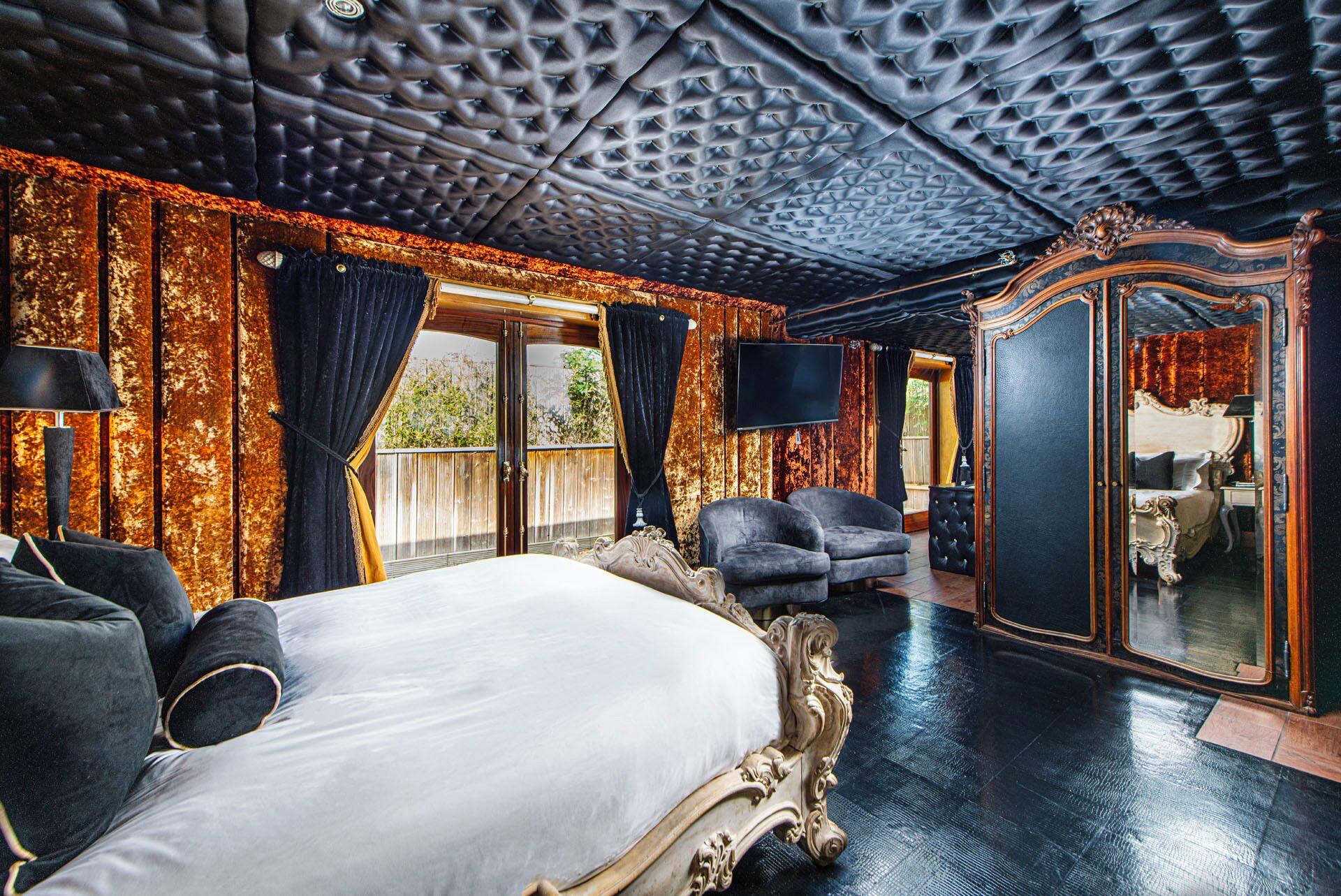 Un dormitorio lujoso con una cama grande, un espejo y una zona de estar.