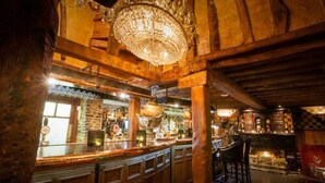 Eine Bar mit Holzbalken, einem Chandelier und einer Theke mit Hockern.