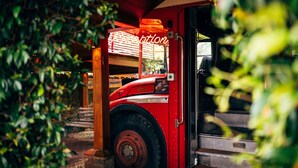 A red fire truck parked in a covered area with a neon sign reading "ptlon" and a wooden bench nearby. - Crazy Bear Hotel-Stadhampton (Oxford)