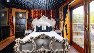 A bedroom with a large bed, ornate headboard, and a view of a wooden deck.