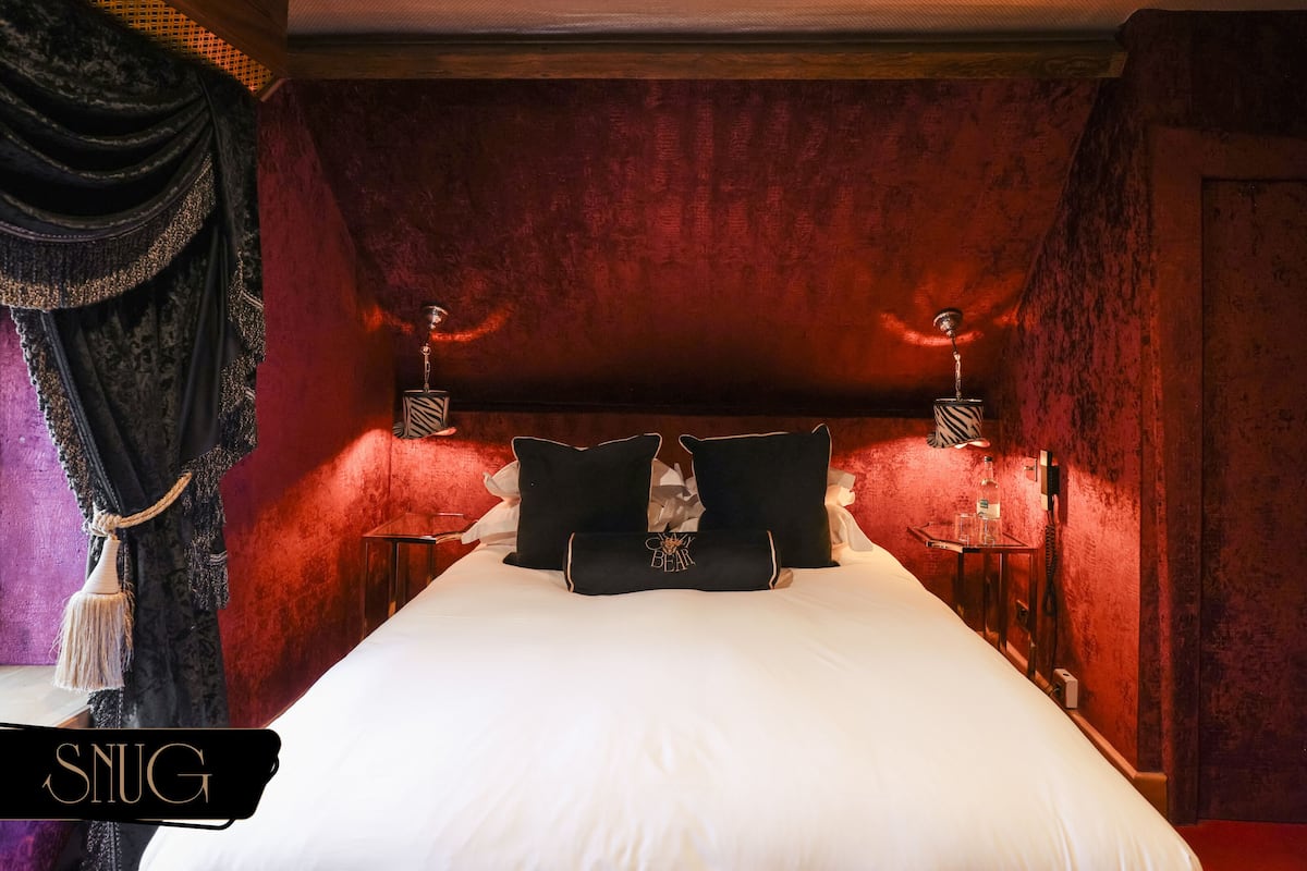 A large bed with white linens, two black pillows, and a decorative headboard.