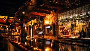 A bar area with a polished counter, a variety of bottles, and a laptop on the shelf. - Crazy Bear Hotel-Stadhampton (Oxford)