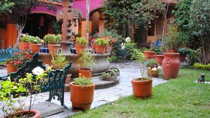 A courtyard with a fountain, potted plants, and a bench.