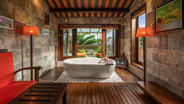 Un baño con bañera independiente, suelo de madera y vistas a través de una ventana.